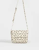 Bandolera color beige de cuerina con solapa, tag metálico y correa larga regulable.