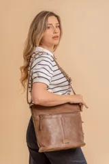 Cartera tipo bandolera de tamaño mediano confeccionada en símil cuero color marrón. Presenta una correa larga regulable, dos compartimientos principales y un bolsillo frontal con cierre de cremallera.