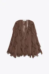 Blusa marrón de gasa con escote en V y manga larga abullonada. Presenta volantes en el mismo tejido y cierre frontal con botones.