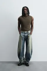 Pantalón de jean celeste con efecto lavado, corte holgado desde la cadera que se estrecha ligeramente en el bajo, tiro medio, cinco bolsillos y cierre frontal con cremallera y botón.