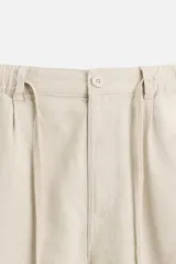 Bermuda negra regular fit confeccionada en tejido con mezcla de algodón y lino. Cintura elástica ajustable con cordón. Pliegues frontales. Bolsillos laterales y traseros de vivo. Cierre frontal con cremallera y botón.