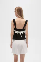 Top negro de viscosa con breteles anchos, escote cuadrado y corte ajustado. Presenta una franja horizontal blanca a la altura del busto.