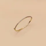 Brazalete rígido dorado con hilera de circonias engarzadas.