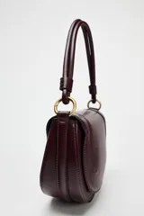 Bolso de hombro ovalado negro con asa de doble tira redonda con detalles metalizados dorados. Cierre imantado y asa de bandolera extraíble con tejido a contraste. Bolso interior con cierre mediante cremallera metálica.