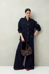 Sobrecamisa oversize de jean azul con cuello camisero, cierre frontal con botones, mangas largas y bolsillos de parche en el pecho.