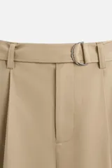 Pantalón negro de corte ancho con cinturón de tela con hebilla metálica y pliegues frontales.