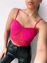 Top fucsia de estilo crop, con detalles en red y tirantes delgados.