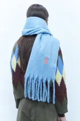 Bufanda azul con flecos en los bordes, ideal para complementar tu outfit.