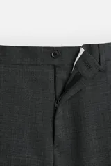 Pantalón de vestir azul marino, de corte slim fit, con bolsillos laterales y traseros. Se ajusta a la cintura con cinturón de cuero marrón.
