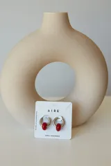 Aros de acero quirúrgico hipoalergénico con forma de argolla plateada y dije circular colgante de piedra natural color azul.