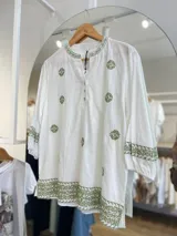 Blusa blanca de lino con bordados florales en verde en cuello, mangas y ruedo. Tiene cuello en V con botones y mangas 3/4.