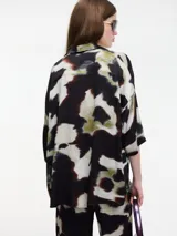 Camisa estampada con botones en la parte delantera, manga corta con sisa caída y cuello camisero.