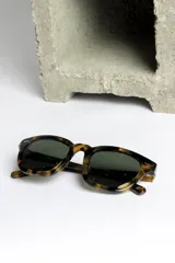 Lentes de sol con montura gruesa color carey y lentes oscuros.