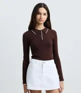 Blusa de punto color marrón, con cuello polo y ribete blanco contrastante. Tiene mangas largas y cierre frontal parcial con botones.