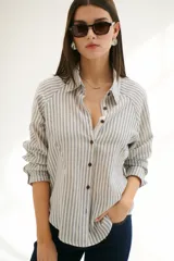 Camisa a rayas verticales color beige y blanco, con cuello clásico, botones marrones y mangas largas.