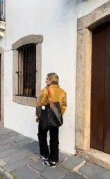 Bolso tote negro con textura símil piel de cocodrilo, doble asa de cuero color marrón y cierre con botón a presión.