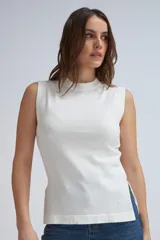 Musculosa blanca de tejido de punto con cuello alto y aberturas laterales.