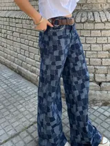 Pantalón de jean ancho (wide leg) de algodón, con diseño de patchwork en tonos de azul que simula un patrón a cuadros, con bordados artesanales a mano en las costuras.