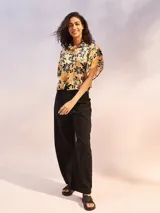 Camisa de manga corta con estampado de flores en tonos amarillo, negro y beige.