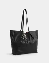 Cartera shopper negra de cuerina con manijas superiores y acceso mediante broche imantado. Incluye charm de perlas en forma de moño.