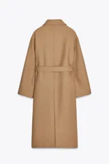 Abrigo largo color camel confeccionado en hilatura con lana. Tiene cuello clásico, cierre frontal con botones ocultos, bolsillos de parche y cinturón del mismo tejido.