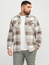 Sobrecamisa a cuadros beige, marrón y blanco, de manga larga y cuello camisero con fit confort. Cierre con botones y bolsillos en el pecho con solapa y broche. Estilo plus size diseñada para cuerpos de talla grande. Tejido de sarga resistente con patrón en “V” característico.