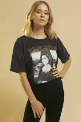Remera negra de algodón con estampado frontal de Amy Winehouse y la inscripción "Winehouse" en color naranja.