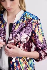 Saco de lentejuelas multicolor con forrería interna y largo a la cadera. Presenta un diseño abierto con mangas tres cuartos y una base de poliéster con forro de viscosa.