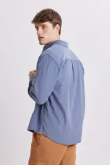 Camisa celeste de micropana con cuello abotonado, manga larga y bolsillo en el pecho.