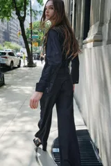 Camisa de denim azul oscuro con cuello con lazos, mangas largas con puños abotonados, bajo redondeado y cierre frontal con botones ocultos.