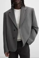 Blazer gris con raya diplomática, corte boxy, cuello con solapas de muesca, manga larga con puño abotonado, bolsillo de vivo en pecho, aberturas en espalda y cierre frontal con dos botones.