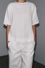 Top de lino color blanco, con cuello redondo y mangas cortas. Detalle de abertura en la espalda ajustable con lazadas.