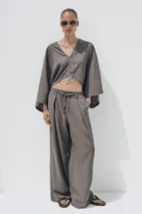 Pantalón blanco de lino, de corte ancho y tiro medio, con cintura elástica ajustable con cordones y bolsillos laterales.