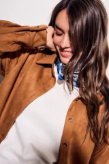 Camisa color marrón de gamuza sintética, de corte recto, con cuello clásico, cierre frontal con botones y mangas largas.