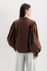 Camisa color beige de algodón con mangas abullonadas y cierre con botones.