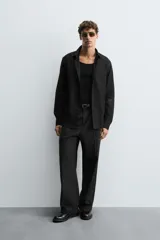 Camisa negra de manga larga con cuello italiano y cierre frontal de botonadura. Presenta un tejido con estructura de fácil cuidado.