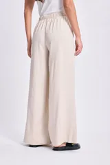 Pantalón de lino color beige, de corte palazzo, con cintura elastizada y cordón ajustable.