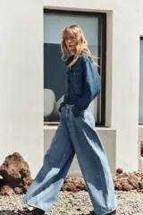 Camisa de denim azul con cuello solapa, manga larga, dos bolsillos delanteros con solapa y cierre frontal con botones a presión.