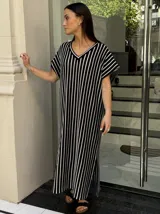 Vestido largo de tejido a rayas horizontales en tonos beige y blanco, con escote en V y mangas cortas tipo murciélago. Presenta tajos laterales en el ruedo.