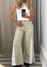 Pantalón de pierna ancha color crudo, con paneles laterales en tela blanca con textura. Presenta un corte que se ensancha hacia el bajo.