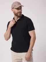 Chomba negra lisa de poliéster, algodón y core spun yarn, con cuello clásico y mangas cortas.