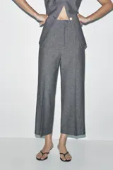 Pantalón culotte gris de tiro alto con bolsillos delanteros de vivo. Pierna ancha y cierre frontal con cremallera y gancho metálico.