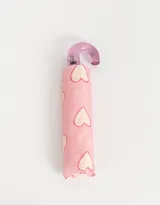 Paraguas corto color rosa con estampa de corazones blancos y mango curvo transparente color lila.