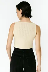 Top sin mangas color crema, de punto crochet con rayas verticales, cuello en v y cierre frontal con broches.