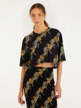 Remera corta negra con estampado de cebras en tonos dorados.