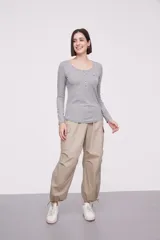 Remera de manga larga entallada en color blanco, confeccionada en algodón. Presenta cuello redondo con una hilera de botones frontales y un pequeño bolsillo en el pecho con detalle de botón.