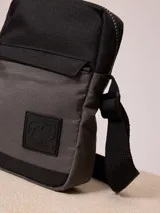 Bandolera negra de poliéster con correa ajustable y logo estampado.