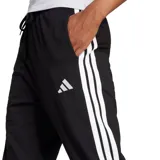 Pantalón de jogging Adidas Essentials para mujer, color negro, con cintura ajustable con cordón y puños elásticos en los tobillos. Presenta el logo de Adidas en blanco en la pierna izquierda.