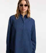 Camisa color ladrillo confeccionada en viscolino, de corte alargado, con cuello clásico, mangas largas, bolsillo delantero y cierre frontal con botones.