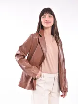 Chaqueta tipo blazer color marrón de cuero sintético, con solapas de muesca y cierre frontal con botones.